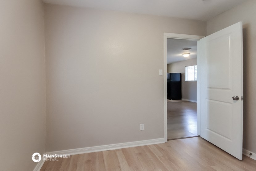 a living room with a white door and a hallway to a bedroom