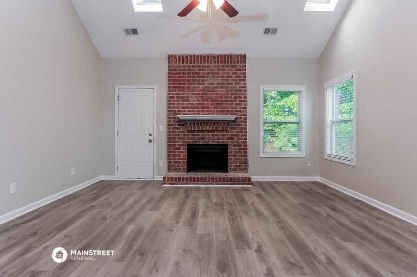 the living room of a home with a brick fireplace and wooden floors