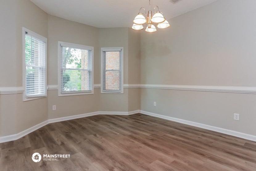 the living room of a house with wooden floors and a chandelier