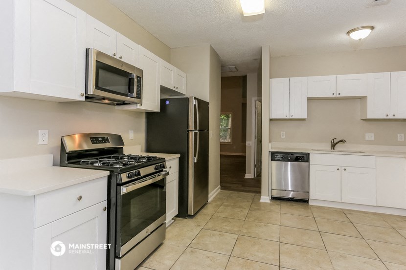 an empty kitchen with stainless steel appliances and white cabinets