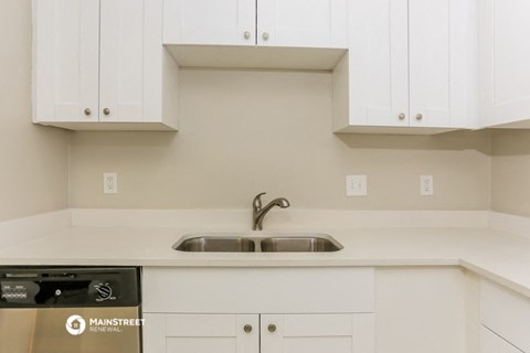 a white kitchen with white cabinets and a sink