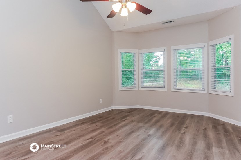 the spacious living room with wood floors and a ceiling fan