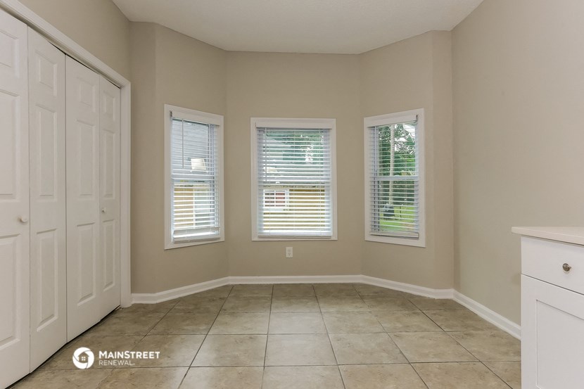 a dining room with three windows and a white door