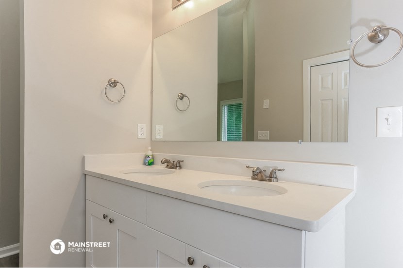 a white bathroom with two sinks and a large mirror