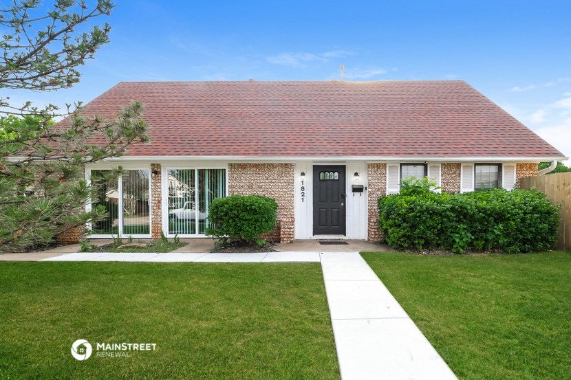 the front of a brick house with a lawn and a black door