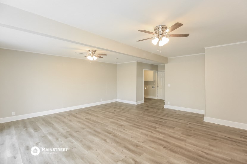 an empty living room with a ceiling fan and wood floors