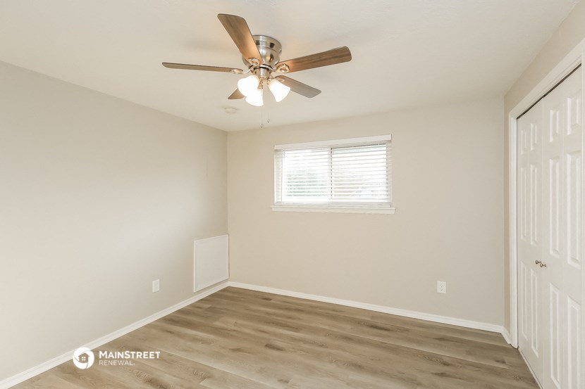 an empty bedroom with a ceiling fan and a window