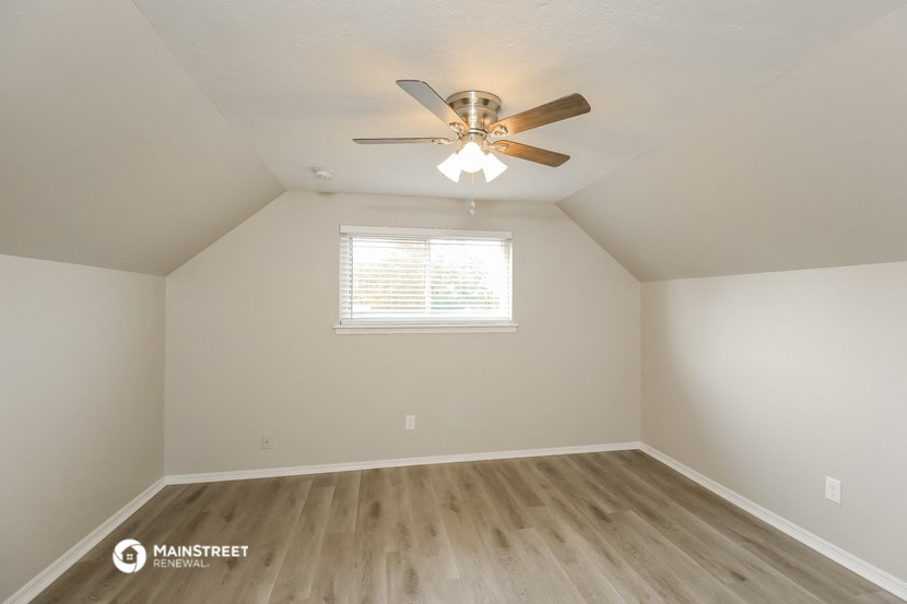 an empty room with a ceiling fan and a window