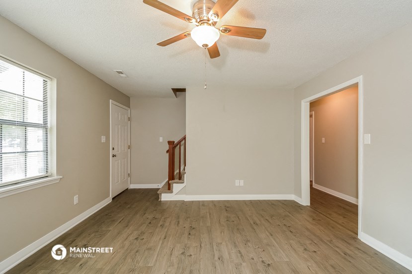 the spacious living room with hardwood floors and a ceiling fan
