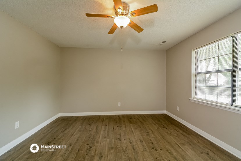 the spacious living room with hardwood floors and a ceiling fan