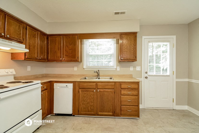 a kitchen with wooden cabinets and white appliances and a door