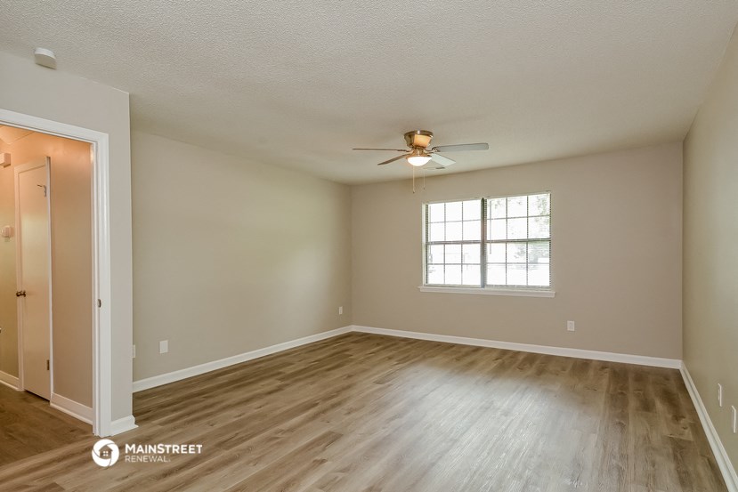 the spacious living room with hardwood floors and a ceiling fan