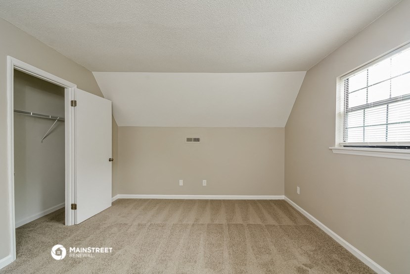 the spacious living room with a closet and a window