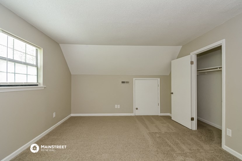 a bedroom with a door to a closet and a window