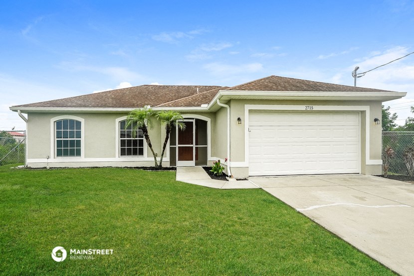 a beige house with a garage and a lawn