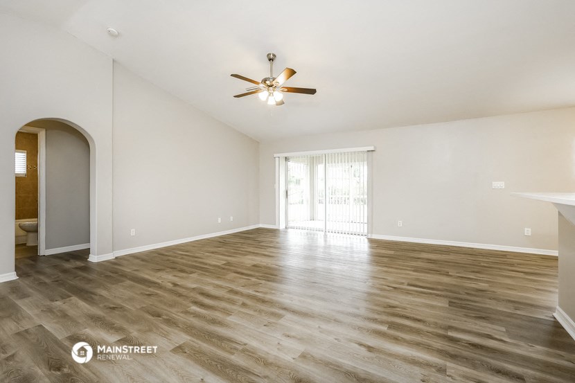 the living room and dining room with wood flooring and a ceiling fan