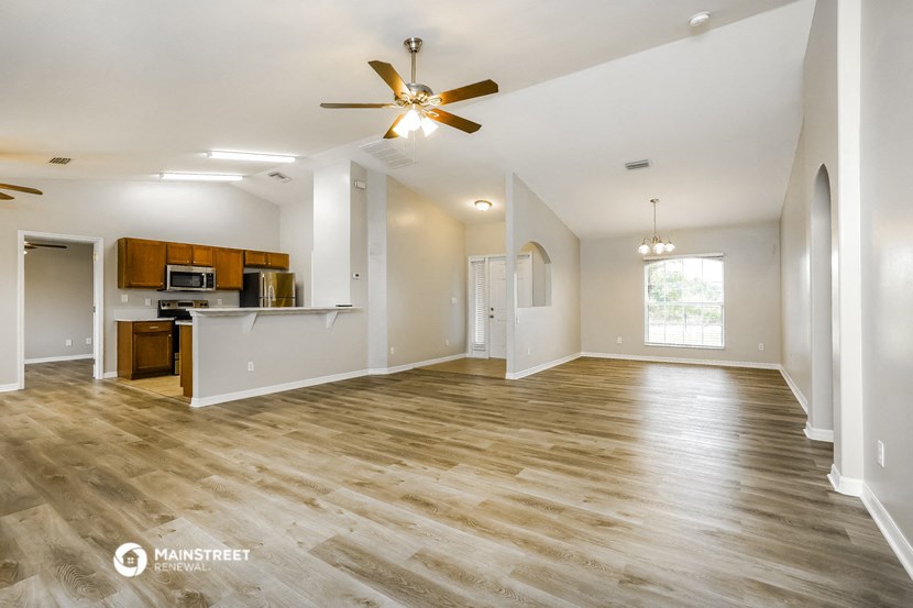 an empty living room and kitchen with a ceiling fan
