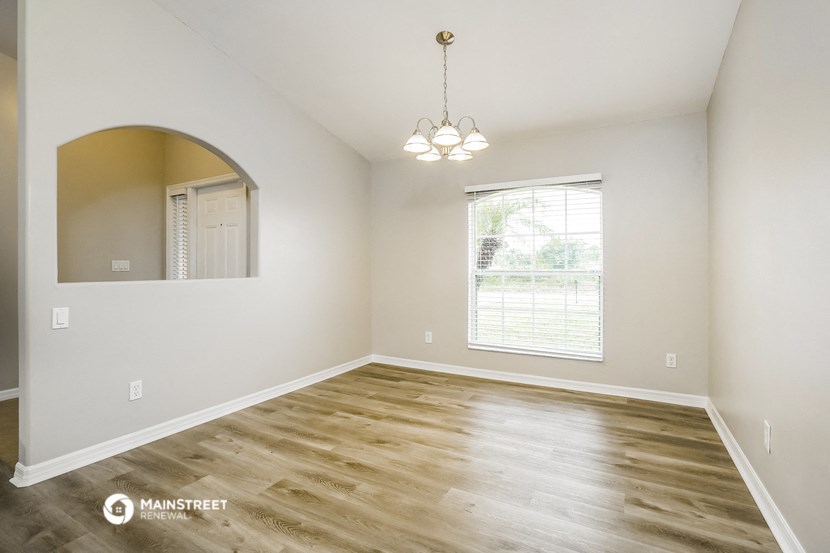 an empty living room with wood flooring and a window