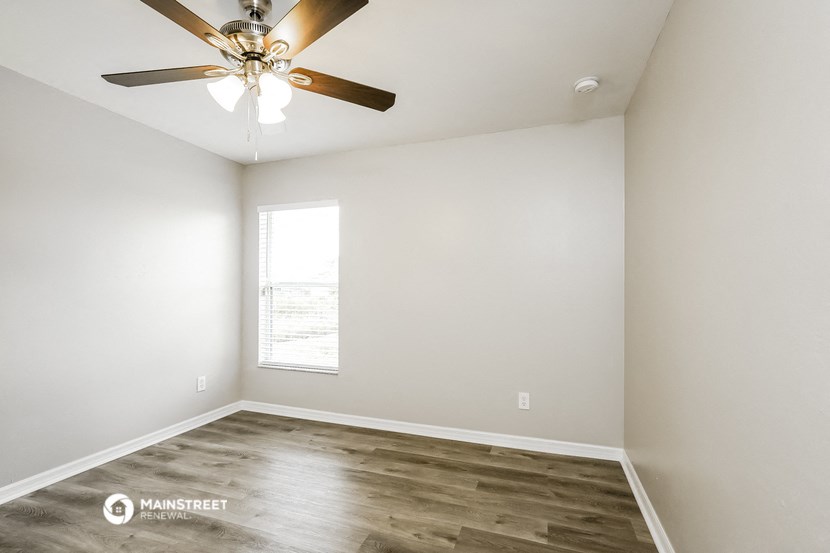 an empty room with a ceiling fan and a window