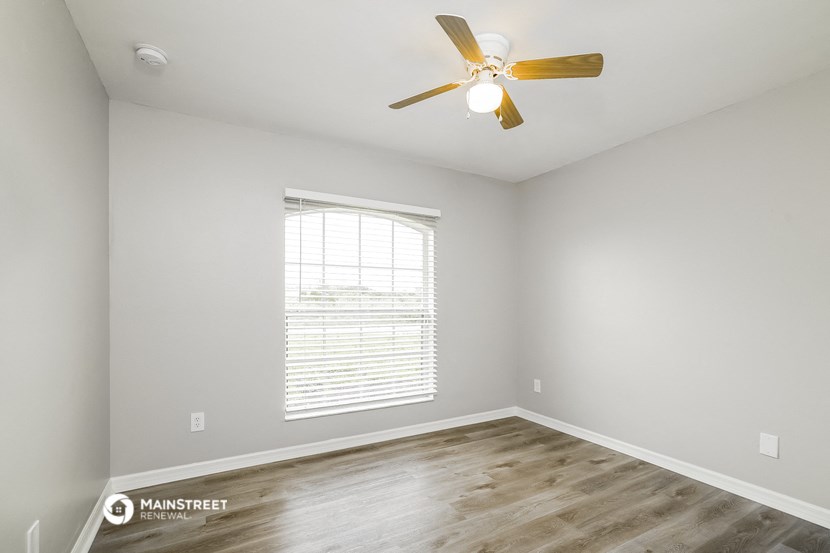 an empty room with a ceiling fan and a window