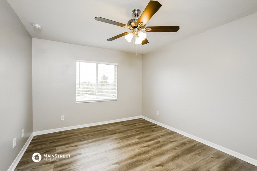an empty room with a ceiling fan and a window