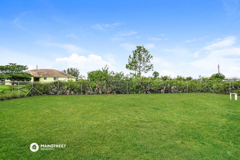 a large yard with a fence and a house in the background