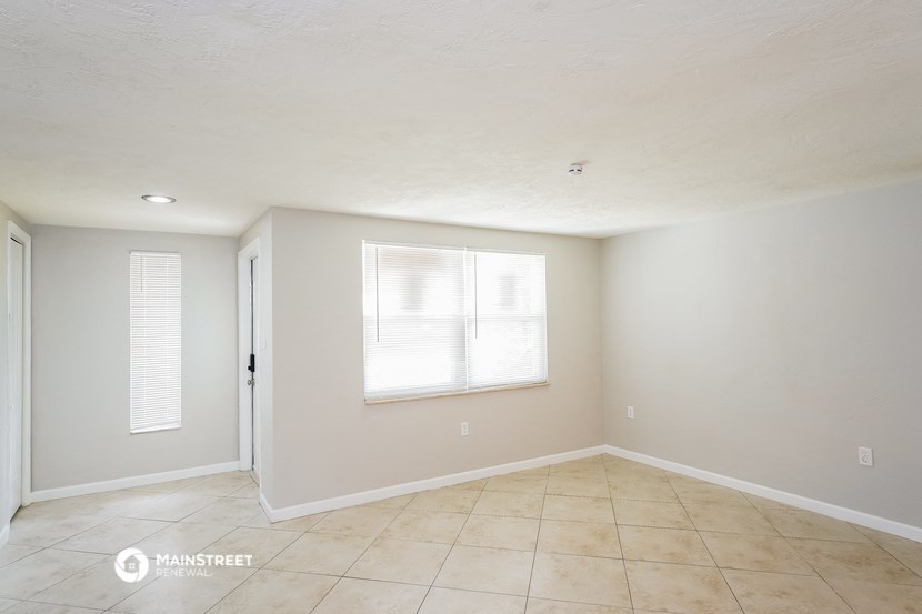 the living room of an empty house with a window and a tiled floor