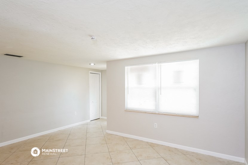 the spacious living room with a large window and tiled floors