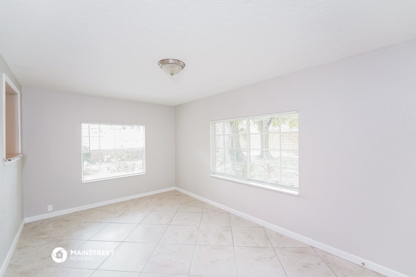 an empty living room with two windows and a tiled floor
