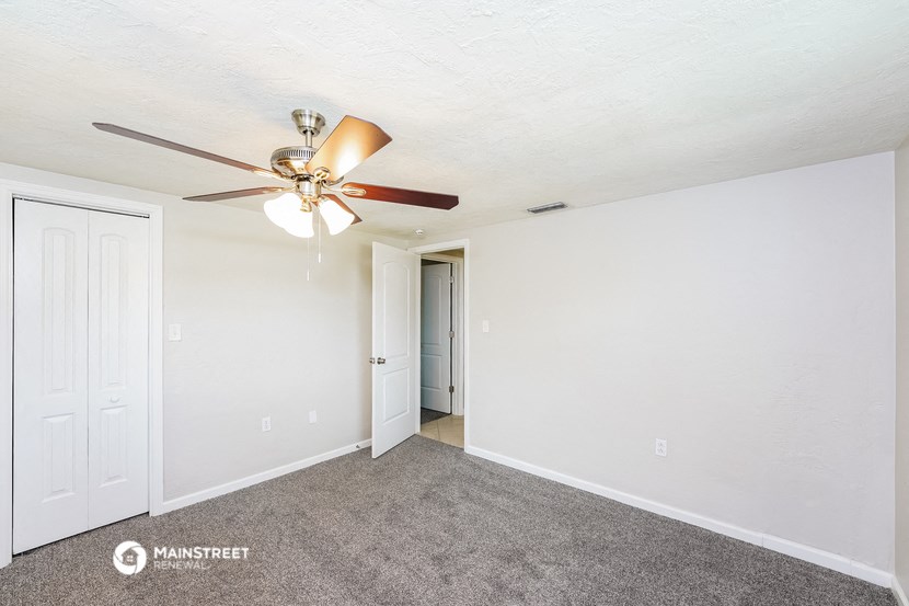 a living room with carpet and a ceiling fan
