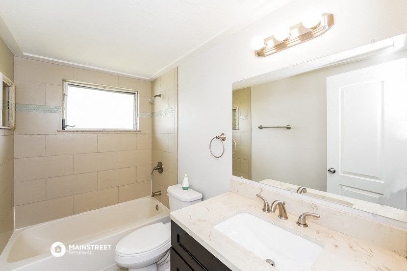 a bathroom with a tub sink and toilet and a mirror
