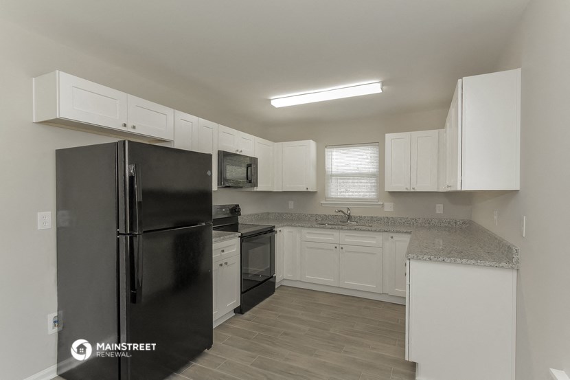 a kitchen with white cabinets and a black refrigerator