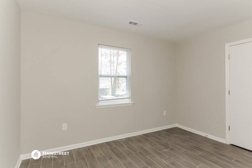the living room of a house with a window and wooden floors