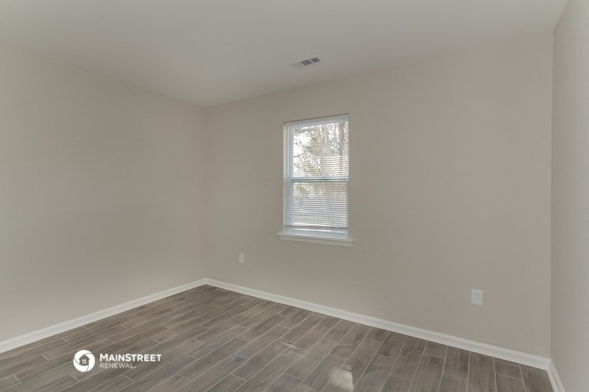 an empty room with a window and wooden floors