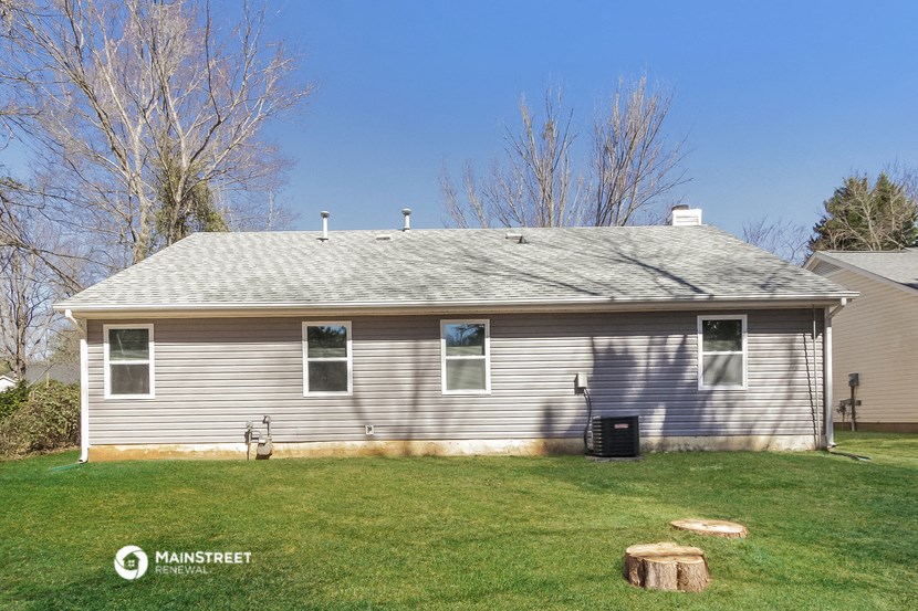 a white house with a gray roof on a grass field