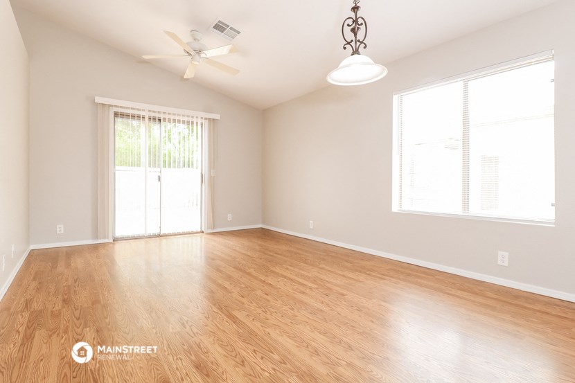 an empty living room with wood floors and a ceiling fan