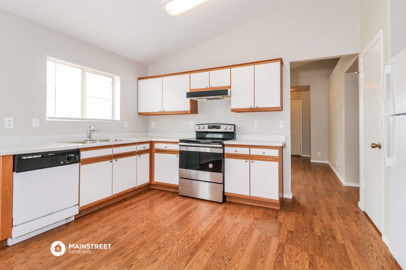 an empty kitchen with wooden floors and white cabinets