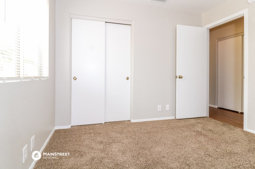 a bedroom with two closet doors and a carpeted floor