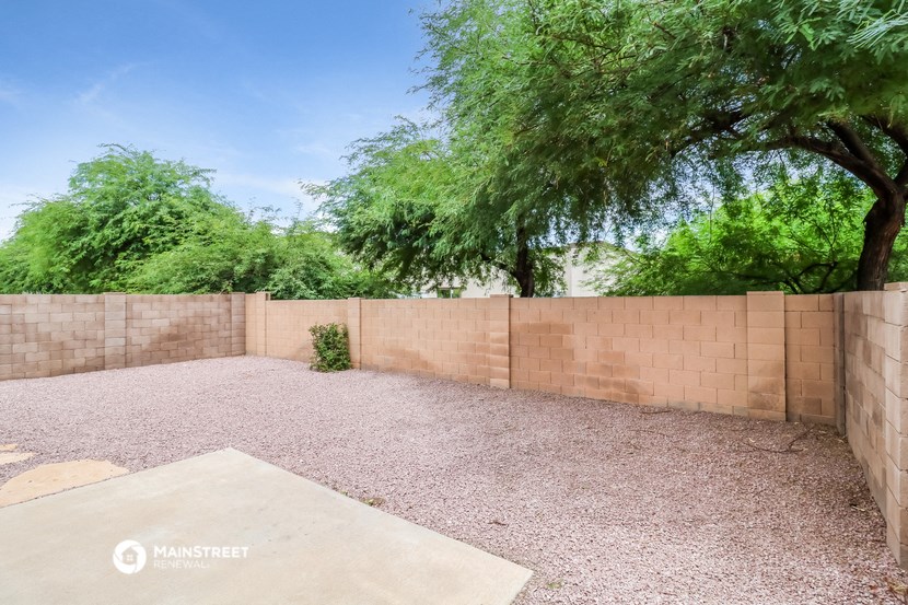 a backyard with a brick wall and a tree