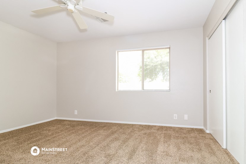 an empty room with a ceiling fan and a window