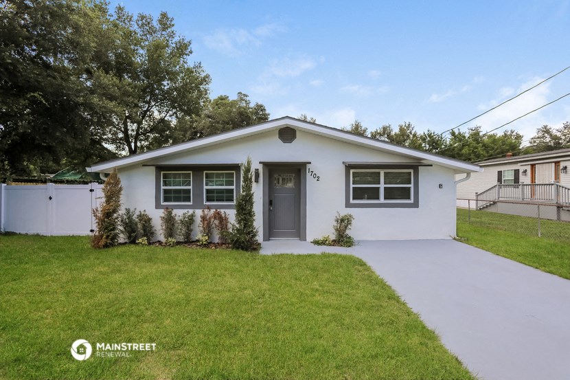 a white house with a gray door and a lawn