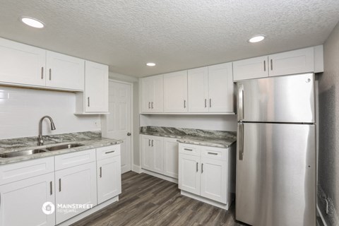 a white kitchen with white cabinets and stainless steel refrigerator