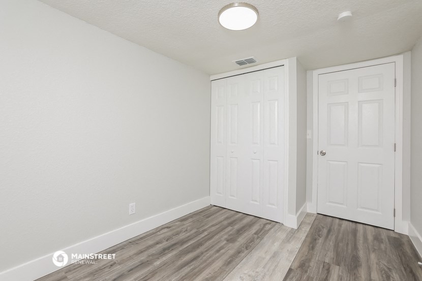 the living room of an apartment with white walls and wood flooring