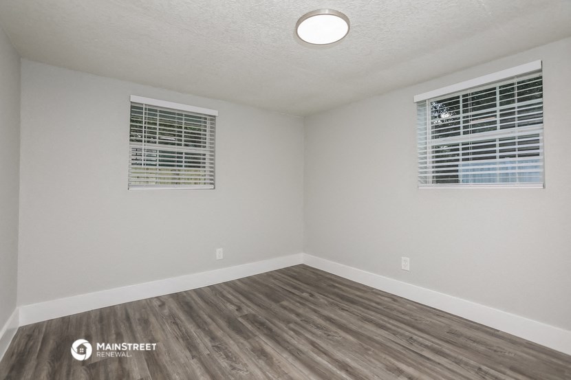 the spacious living room with wood flooring and two windows