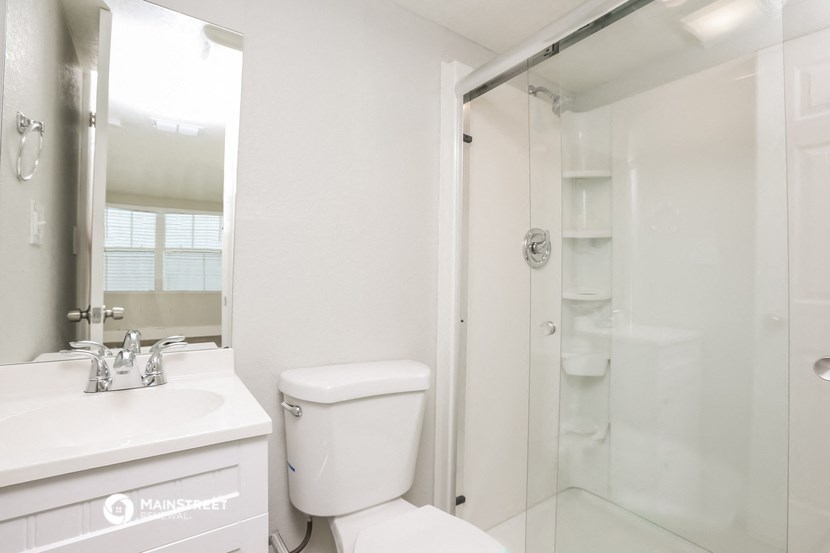 a white bathroom with a shower and a toilet and a sink