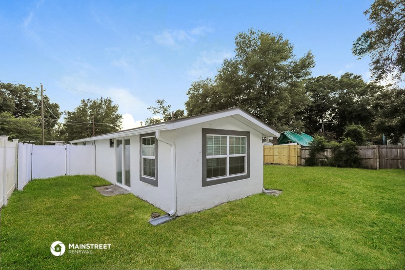 a small white house in a backyard with a yard and a fence