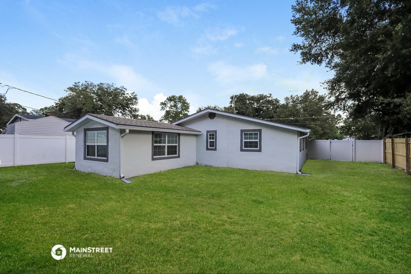 a small white house with a yard and a fence