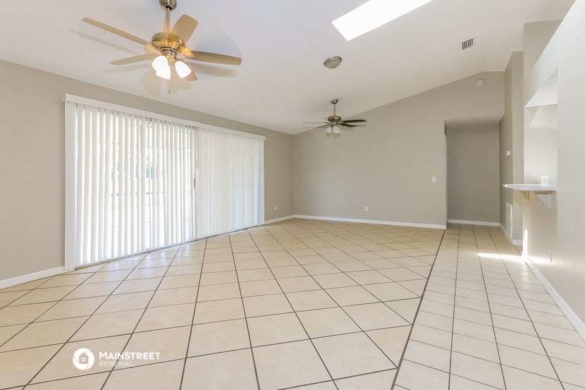 a spacious living room with tile flooring and ceiling fans