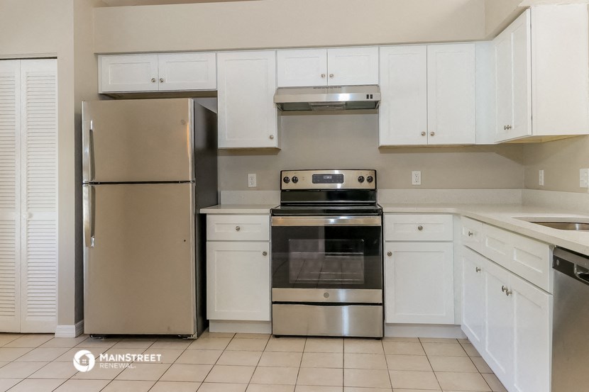 a white kitchen with stainless steel appliances and white cabinets