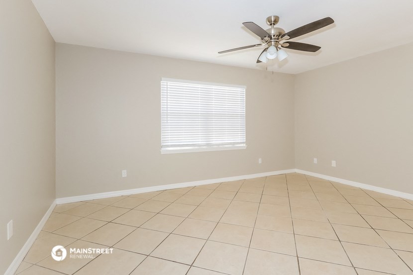 the spacious living room with tiled flooring and a ceiling fan